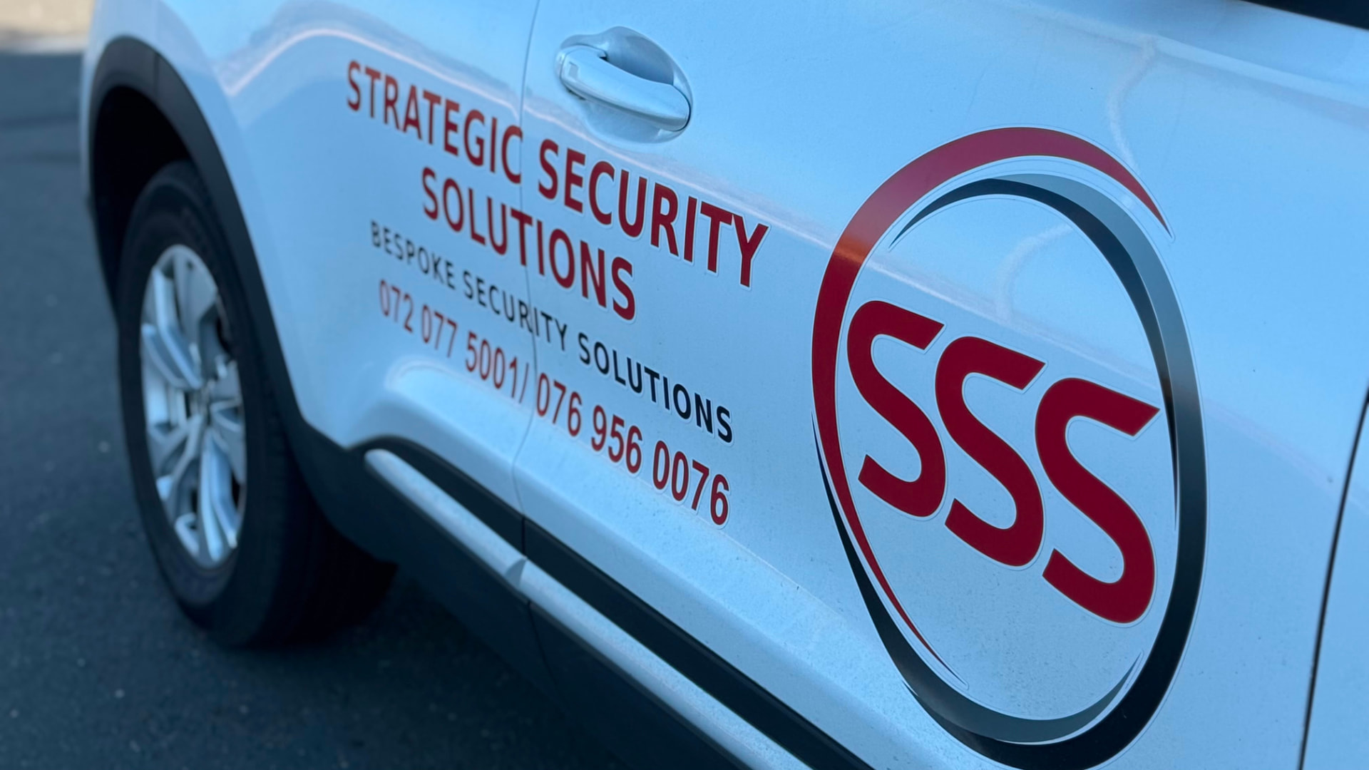 Close-up of the Strategic Security Solutions logo and contact numbers on a patrol vehicle