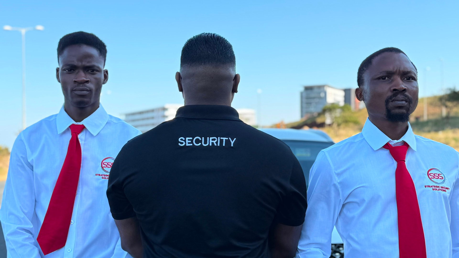 SSS officers standing to attention beside a branded response vehicle